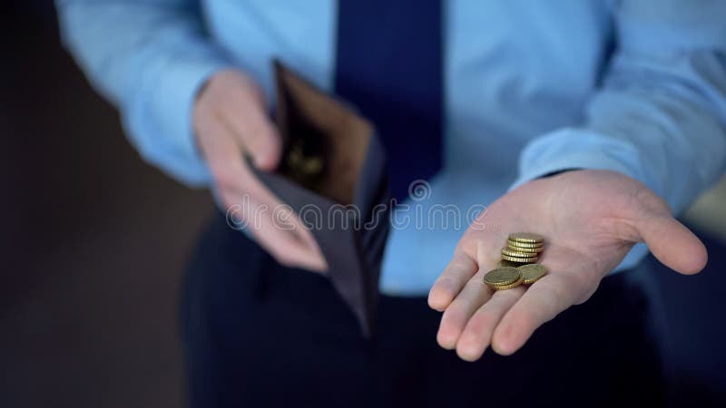 Man in suit holding coins in open palm, giving donations, low income, poverty, stock photo