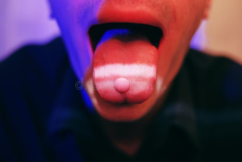 A man swallows a pill, a pill on his tongue, drugs, MDMA. A man swallows a pink pill in a club