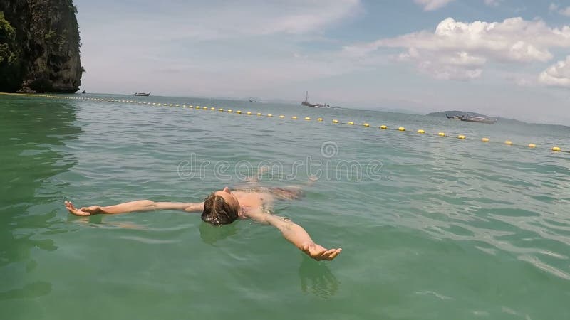 Man swimming on back in sea action camera pov of young guy lying on water on beautiful beach