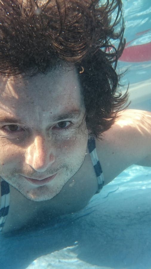 Man in swimming pool underwater making selfie. Male diving under water from closeup portrait front view. Man in swimming pool underwater making selfie. Male diving under water from closeup portrait front view.