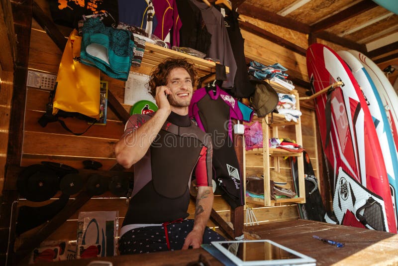 Man in swimsuit talking on smartphone in the surf shack stock images Man in swimsuit talking on smartphone in the surf shack stock images