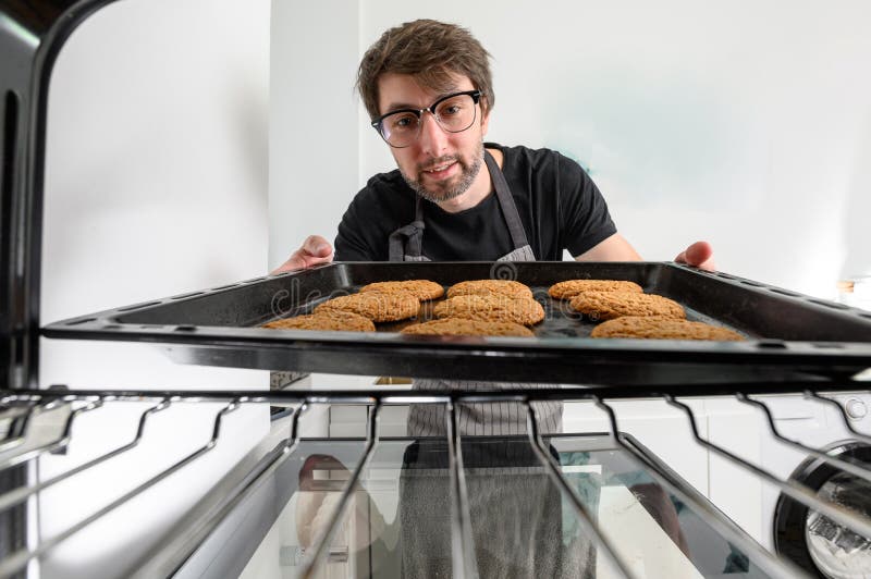 Male Cook Baking Cookies in the Oven. Inside View of the Oven Stock