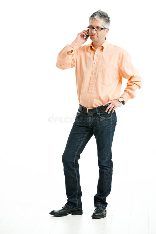 Grey haired man wearing jeans and orange shirt standing and talking on mobile phone. Isolated on white. Grey haired man wearing jeans and orange shirt standing and talking on mobile phone. Isolated on white.