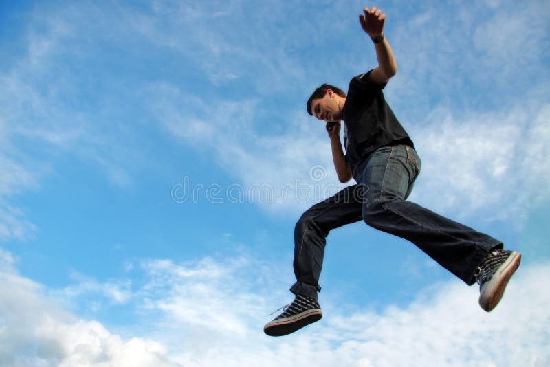 Young man talking on phone midair, blue sky and cloudscape on background