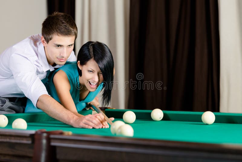 Man teaching girl to play billiard