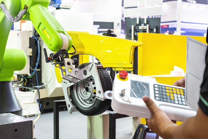 Man technician enter program command or operated robot with grip pass wireless remote for catch and control wheel and tire stock photo
