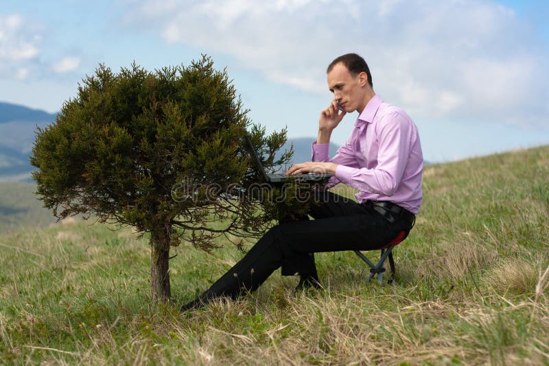 Man with telephone and computer on tree