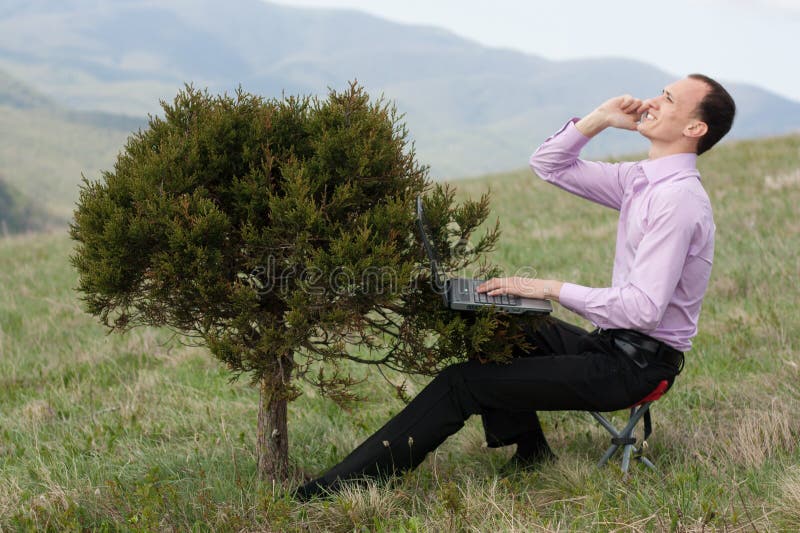 Man with telephone and computer on tree