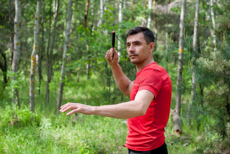 A Man Throws a Knife at a Target in the Summer Forest. Throwing a Knife