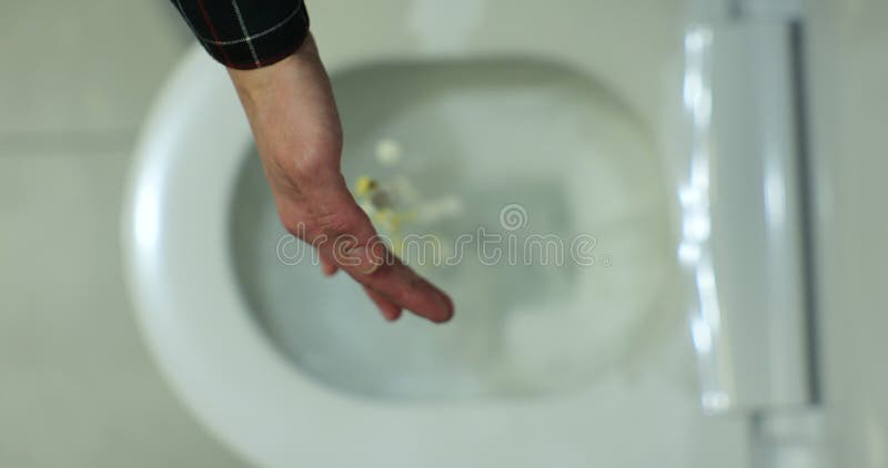 Hand throwing pills down a toilet Stock Photo - Alamy