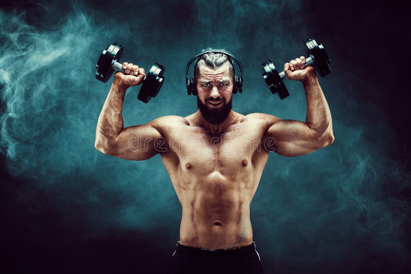 Man training muscles with dumbbells in studio on dark background with smoke. royalty free stock image Man training muscles with dumbbells in studio on dark background with smoke. royalty free stock image