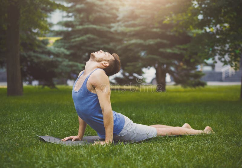 Man training yoga in cobra pose outdoors