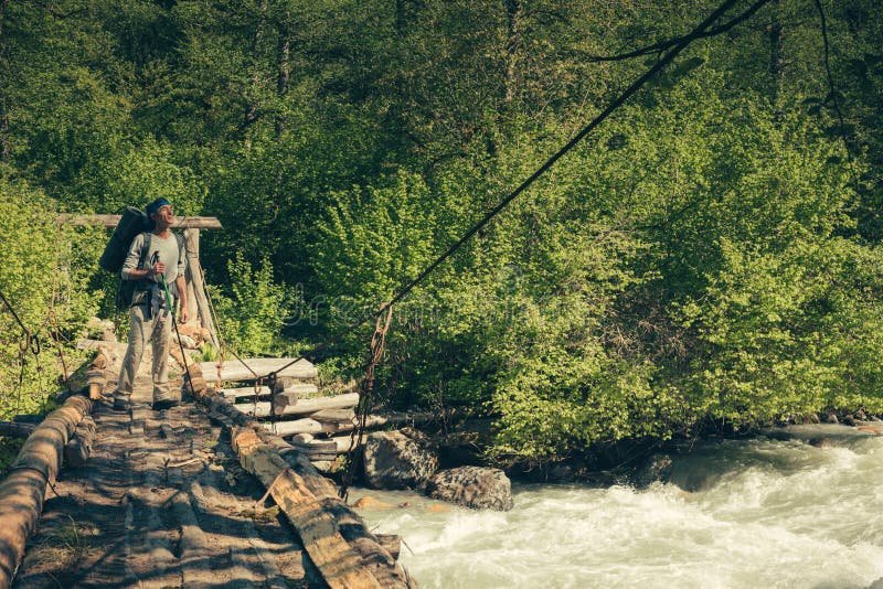 A man traveling with backpack hiking on bridge over river. Travel Lifestyle concept. royalty free stock photos A man traveling with backpack hiking on bridge over river. Travel Lifestyle concept. royalty free stock photos