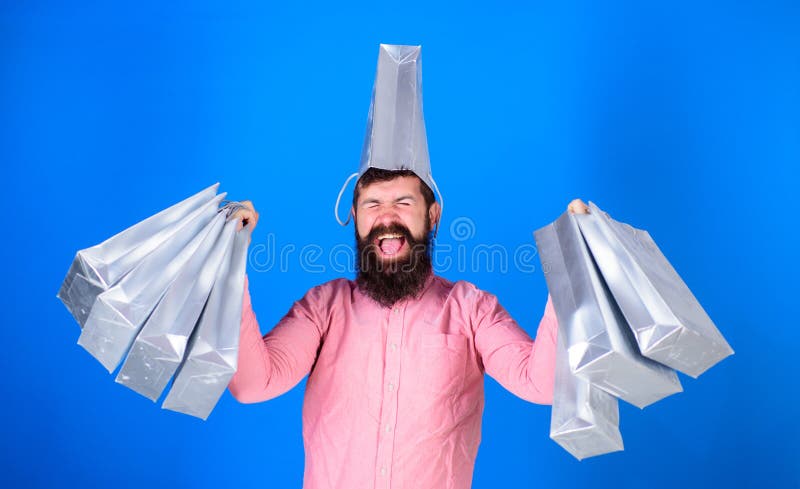 Man with trendy beard wearing pink shirt and silver bag on his head isolated on blue background. Shopping champion royalty free stock image Man with trendy beard wearing pink shirt and silver bag on his head isolated on blue background. Shopping champion royalty free stock image