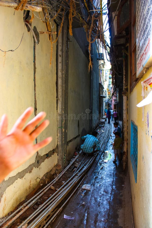 Delhi, India - August 18, 2009: man and two child in a very narrow alley of delhi full of rubbish, exposed pipes, electric cables stock images Delhi, India - August 18, 2009: man and two child in a very narrow alley of delhi full of rubbish, exposed pipes, electric cables stock images