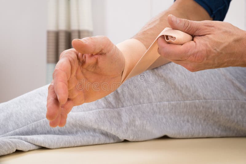 Close-up Of A Man Tying Elastic Bandage To His Wrist 
