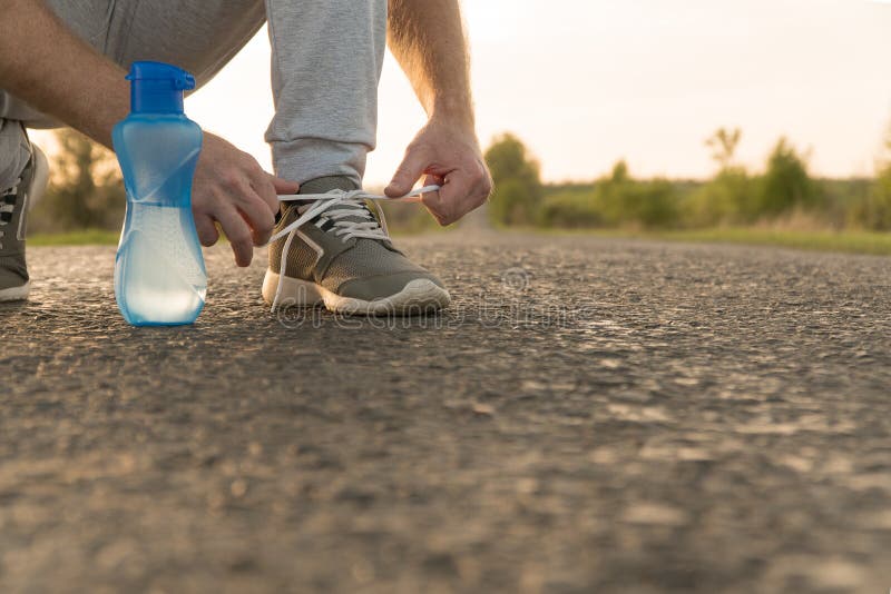 Man Tying Running Shoes. Water Bottle is on Asphalt. Stock Image - Image of  sports, shoes: 146083941