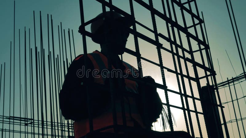 Man in uniforme staven voor het verstevigen van breiwerk op bouwterrein.