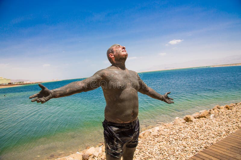 Man uses therapeutic mud, enjoying the sun