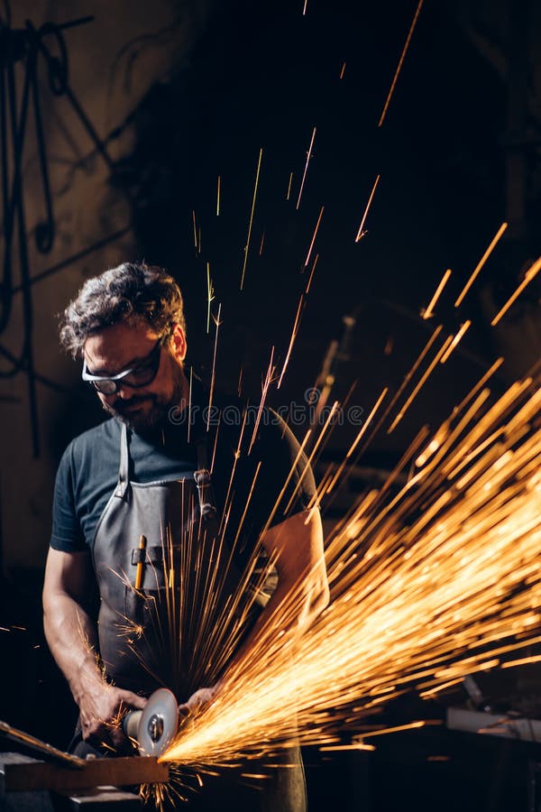 Man Using Angle Grinder in Factory and Throwing Sparks Stock Image