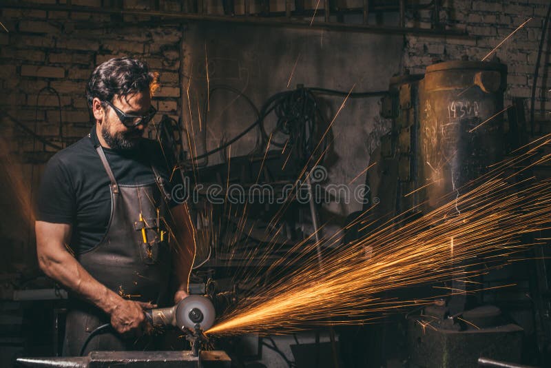 Man Using Angle Grinder in Factory and Throwing Sparks Stock Image