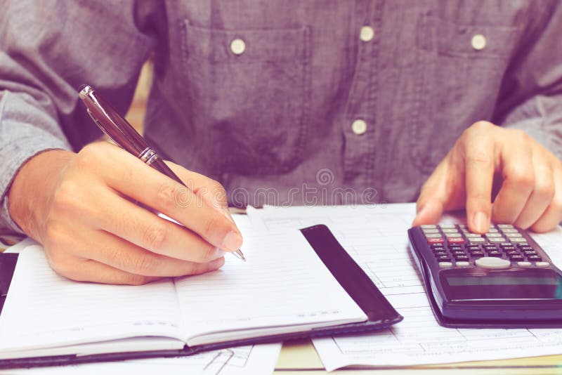 Man Using Calculator and Writing Note in Home Office. Stock Image