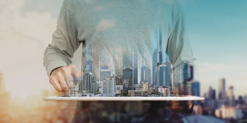 A man using digital tablet, and modern buildings hologram. Real estate business and building technology concept stock photos