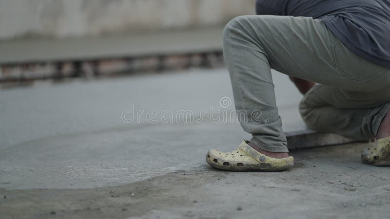 Man using float trowel to smooth the top layer of freshly poured hardening concrete in the road during construction. - stock video footage