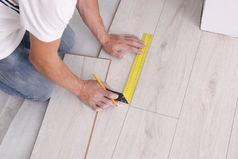 Man Using Measuring Tape during Installation of Laminate Flooring