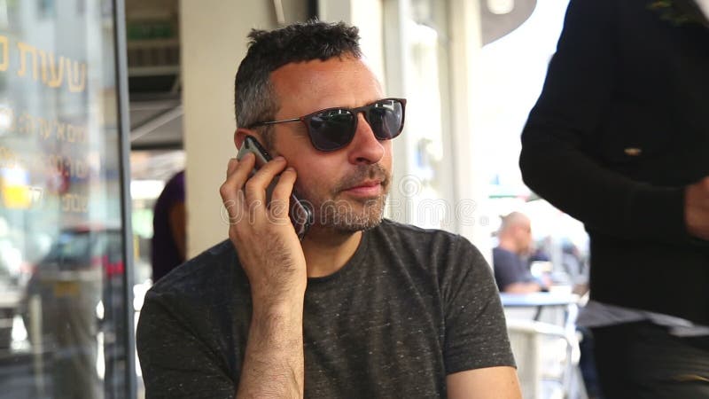 Young trendy man enjoy coffee and his mobile phone. Hot cafe video