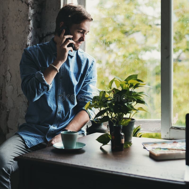 Man Using Mobile Phone Sitting by the Window Break Time Stock Photo