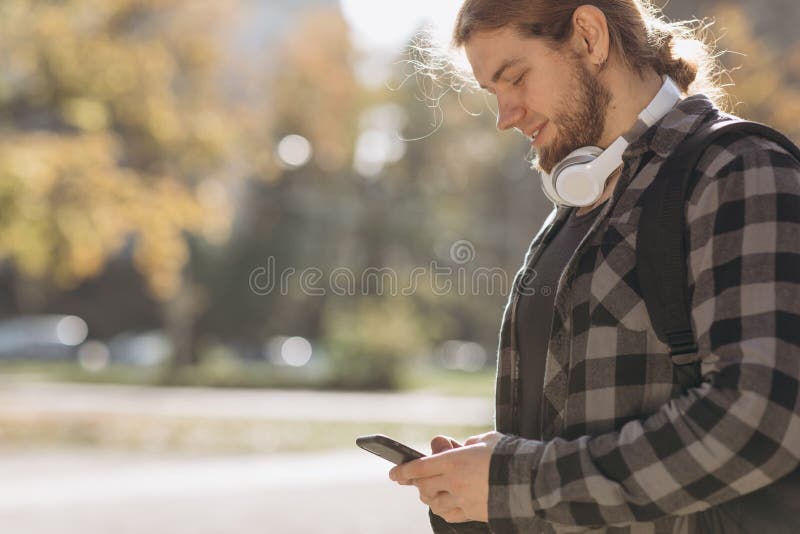View of a Young attractive man using smartphone. Young urban man using smart phone holding mobile smartphone using app texting sms message. Bearded man playing on smartphone. View of a Young attractive man using smartphone. Young urban man using smart phone holding mobile smartphone using app texting sms message. Bearded man playing on smartphone