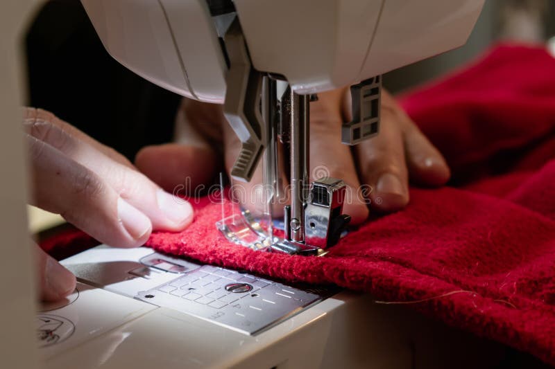 Man Using a Sewing Machine with a Red Garment, for Repair Work