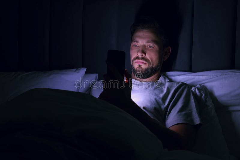 Man using smartphone in bed at night. Internet addiction royalty free stock images