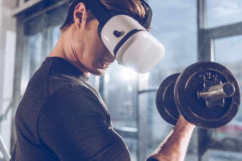 Man in Virtual Reality Headset Exercising with Dumbbell in Gym Stock
