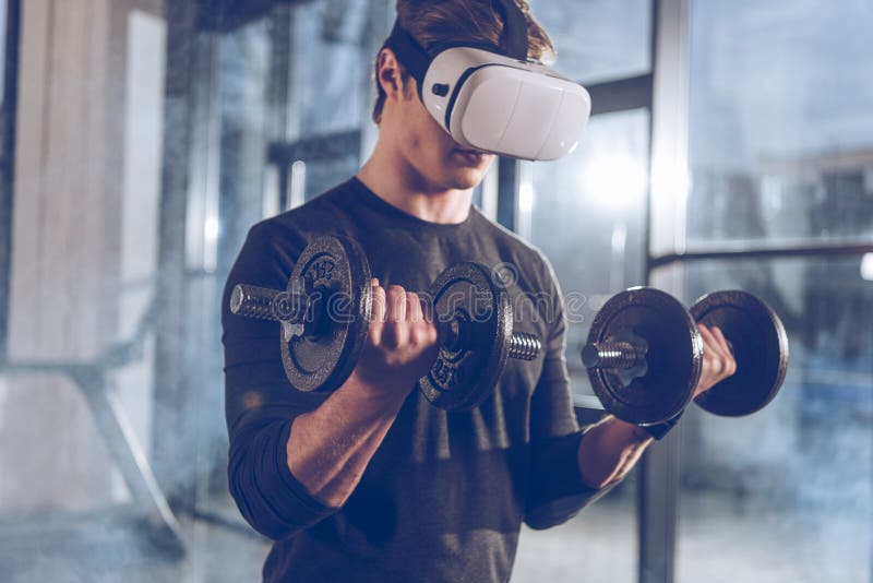 Man in Virtual Reality Headset Exercising with Dumbbells in Gym Stock