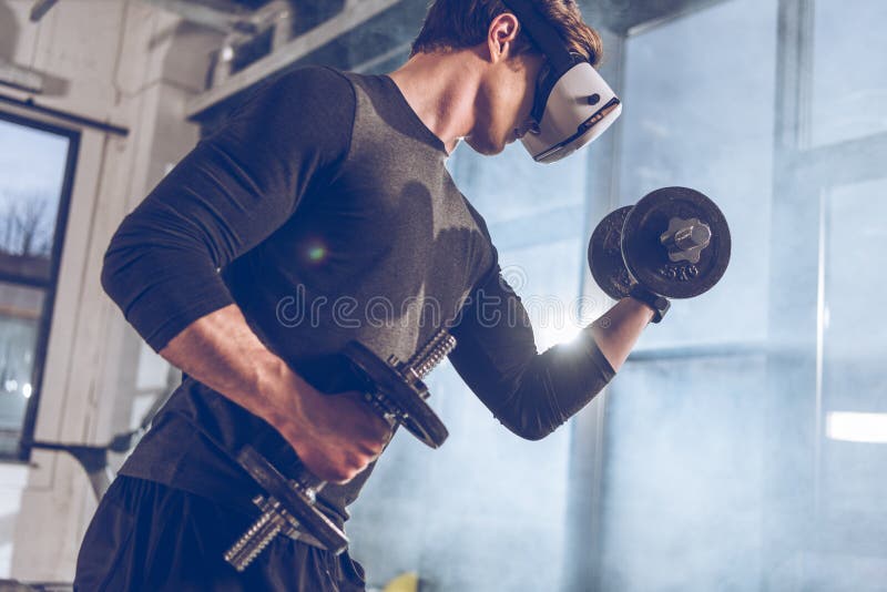 Man in Virtual Reality Headset Exercising with Dumbbells in Gym Stock