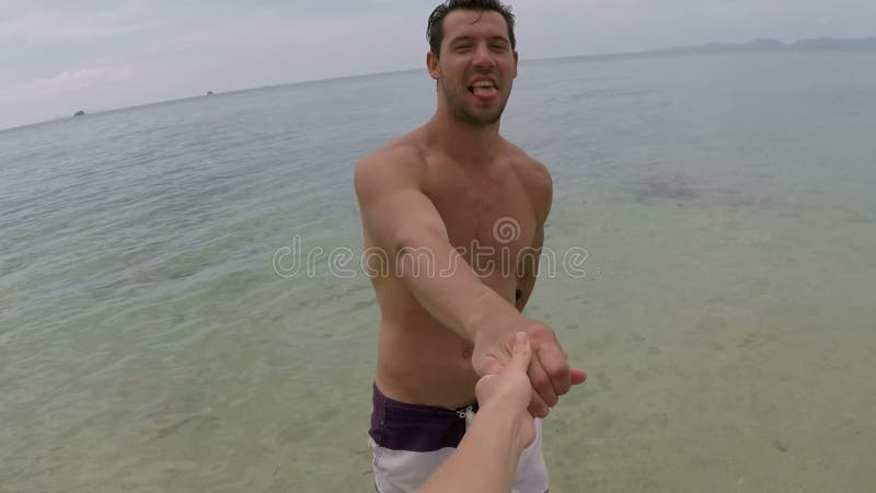 Man walk in sea water holding hand talking action camera pov of young couple on seaside