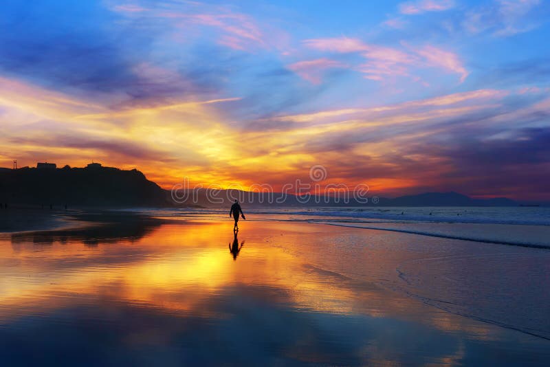 Man walking on the beach at sunset