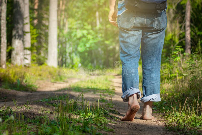 Man walking on footpath forest. Close-up of bare feet soiled with ground. healthy lifestyle.