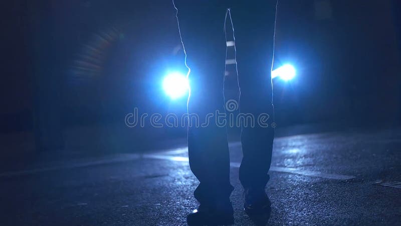 Man walking in front of car headlights