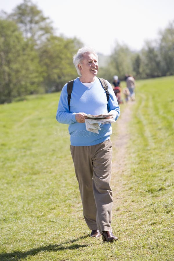 Man Walking Outdoors Holding Map Smiling Stock Photo Image 5559480