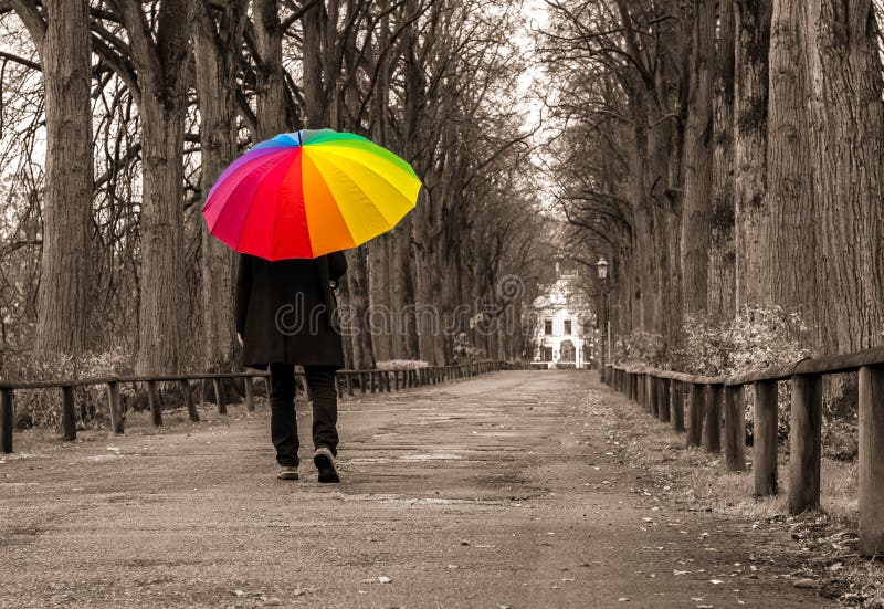 Man walks under rainbow umbrella