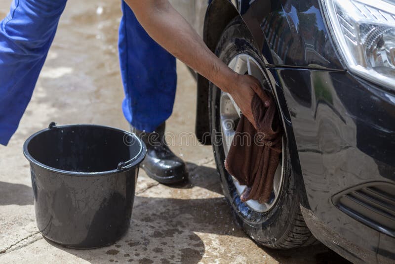 a man washes a car wheel with a rag.