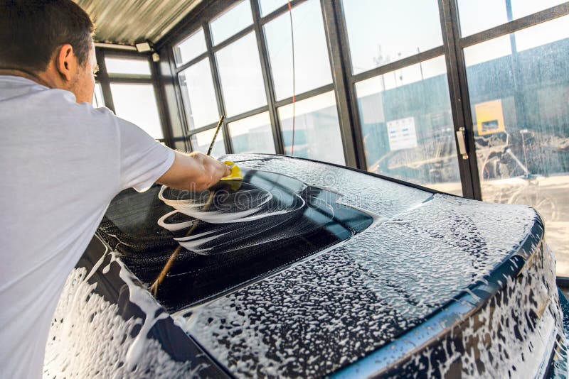 Selfservice Car Wash. a Man Washes Off the Foam from His Car with