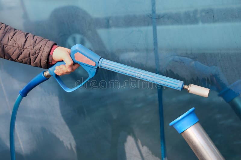 Man washes his car at car wash. Cleaning with soapy at self-service car wash. Male hand close up.