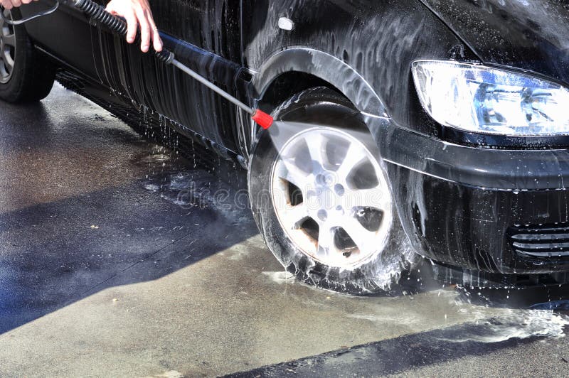 Man Washing His Car Under High Pressure Water in Service Stock Photo