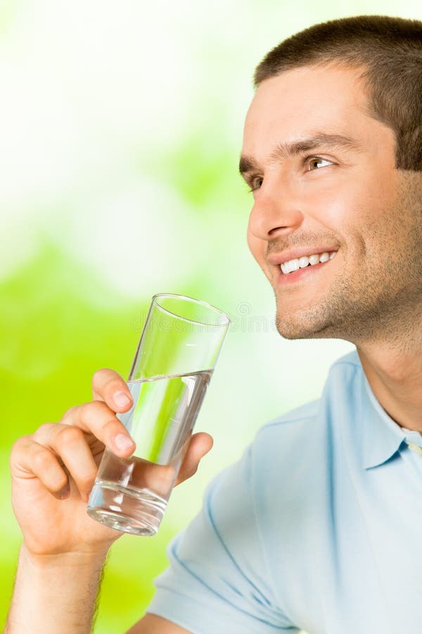 Young man with glass of water, outdoors. Young man with glass of water, outdoors