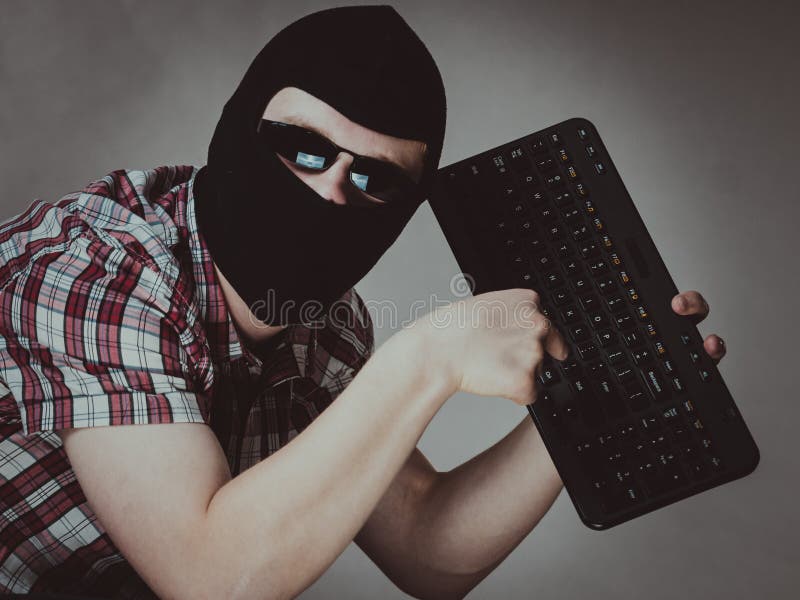 Man wearing balaclava holding keyboard royalty free stock image