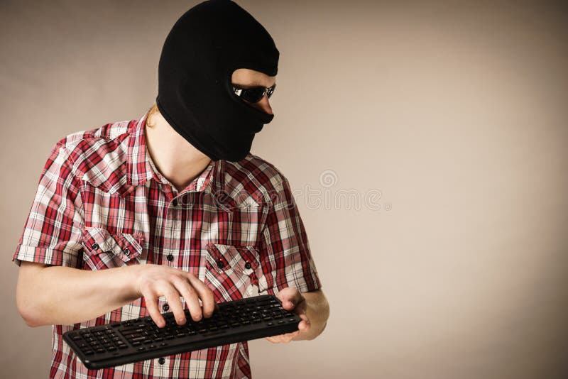 Man wearing balaclava holding keyboard royalty free stock image